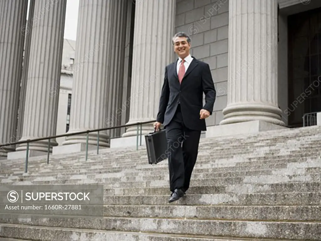 Low angle view of a male lawyer walking down the steps of a courthouse