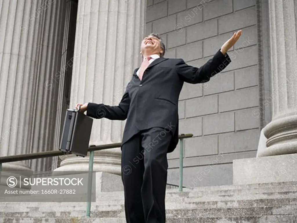 Low angle view of a male lawyer holding a briefcase and laughing