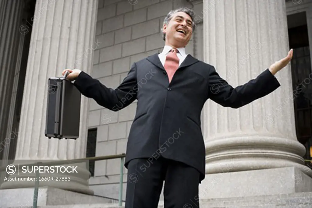 Low angle view of a male lawyer holding a briefcase and laughing