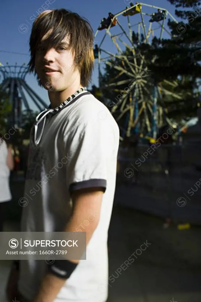 Side profile of a young man standing in an amusement park