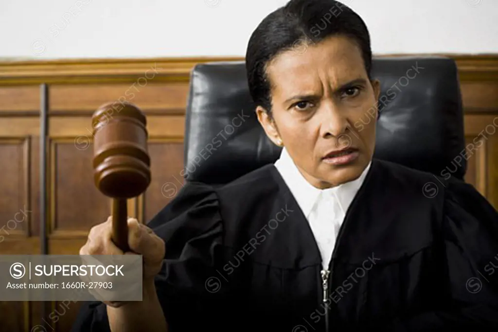 Portrait of a female judge holding a gavel and looking serious