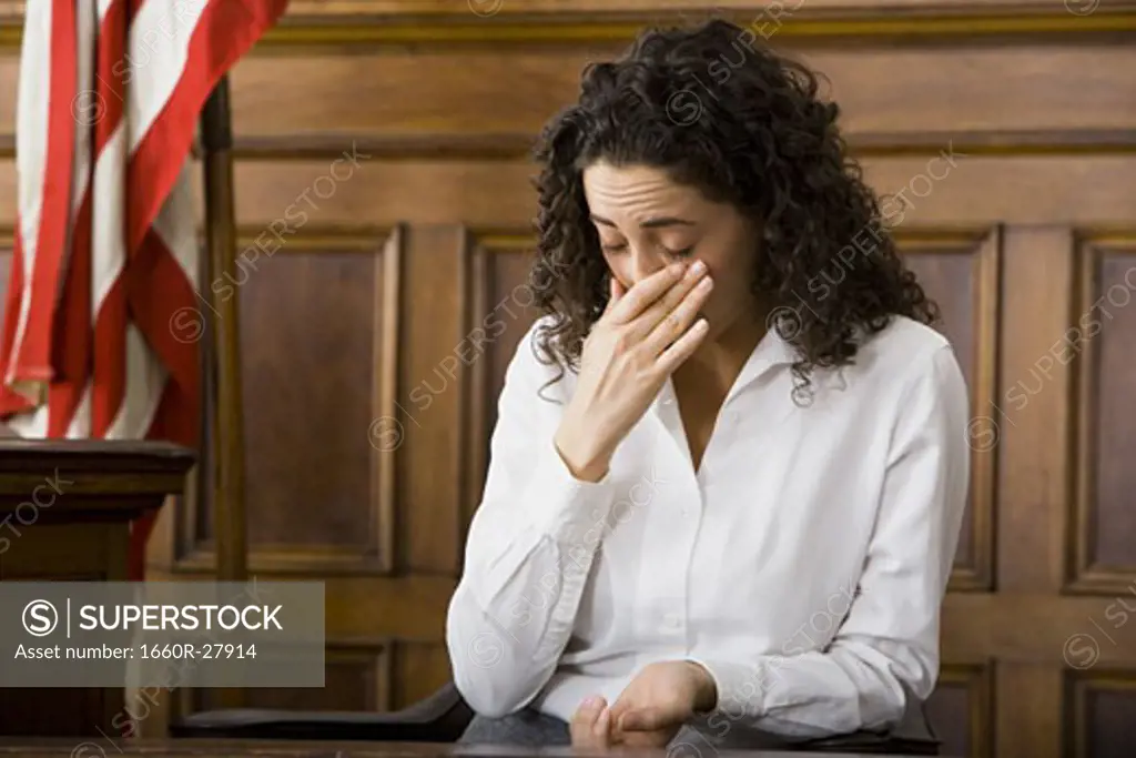 An upset female witness sitting in a courtroom