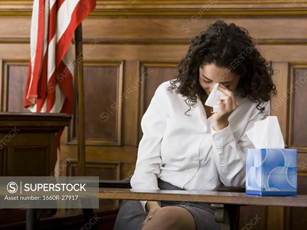 An upset female witness sitting in a courtroom