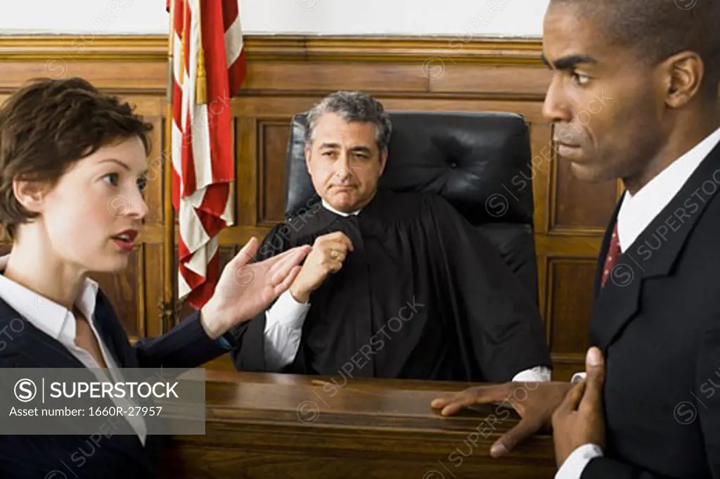 Two lawyers standing face to face in front of a male judge in a courtroom