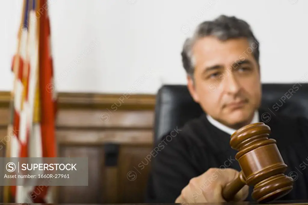 A male judge hitting a gavel on the bench