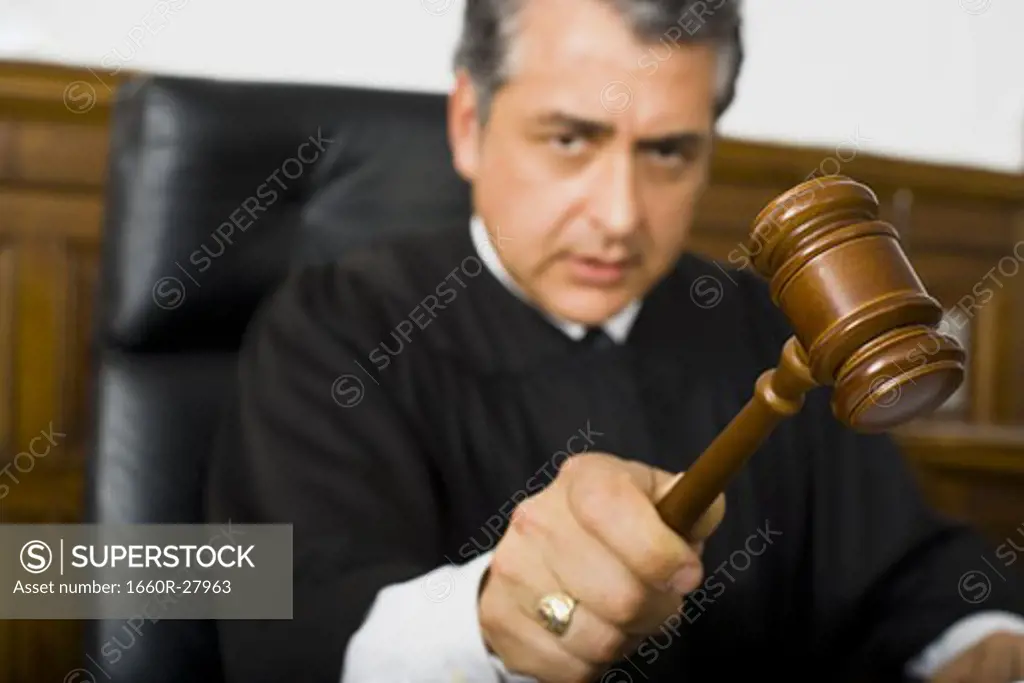 A male judge hitting a gavel on the bench