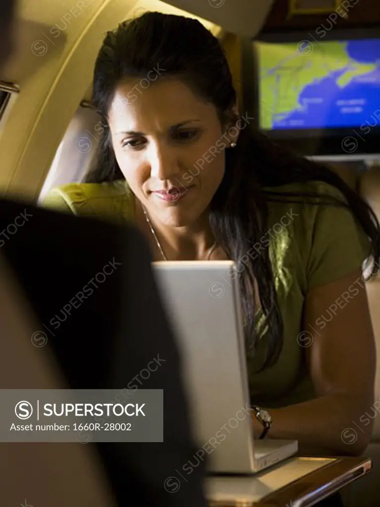 A businesswoman using a laptop in an airplane