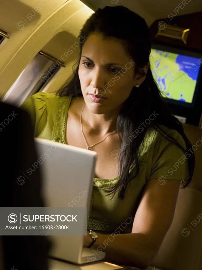 A businesswoman using a laptop in an airplane
