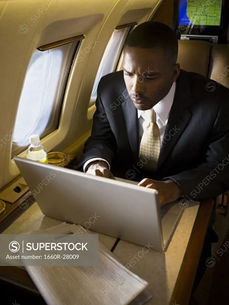 Businessman using a laptop in an airplane