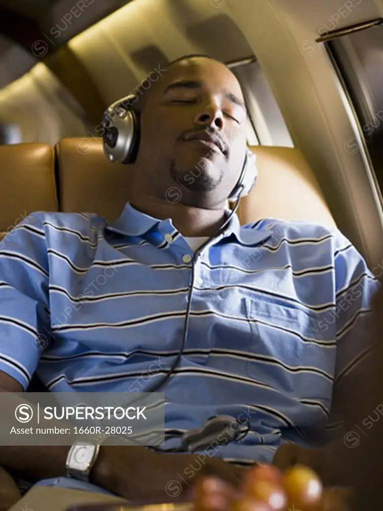 A man listening to music on headphones in an airplane