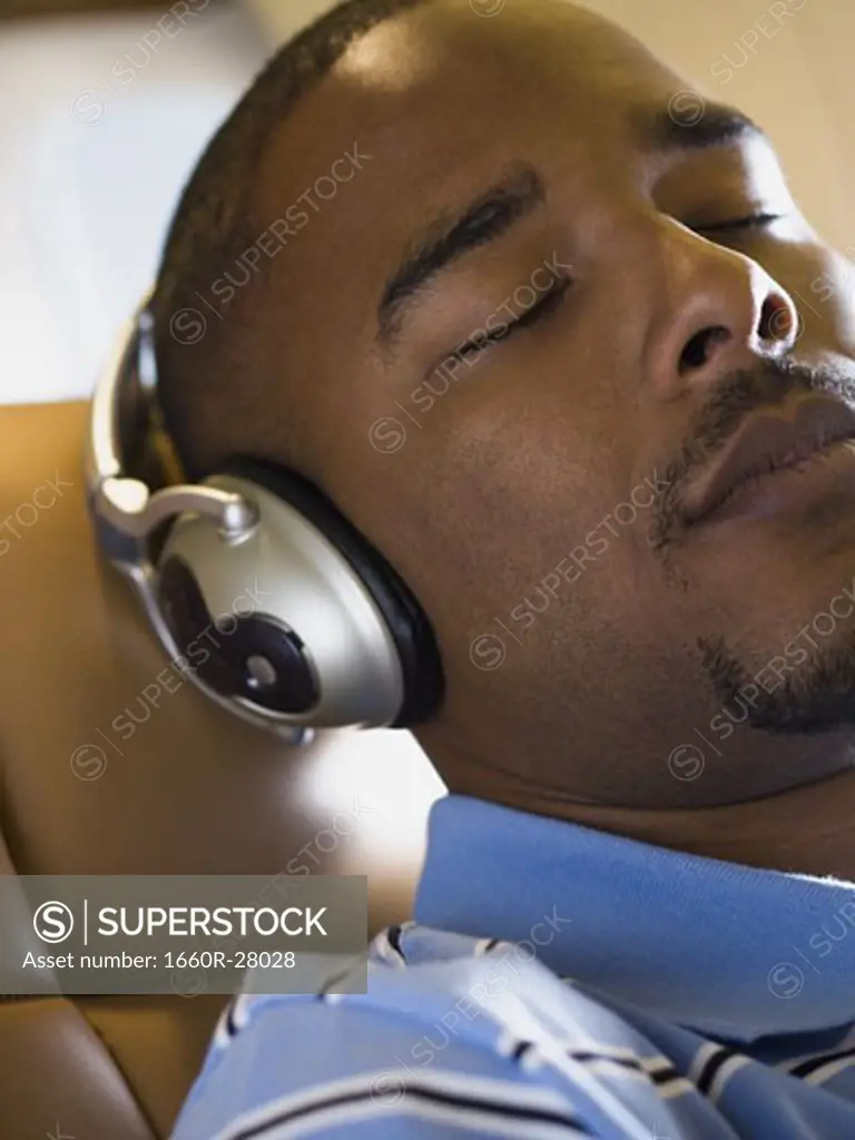 Close-up of a man listening to music on headphones in an airplane
