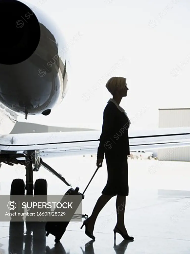 Profile of a businesswoman pulling a suitcase