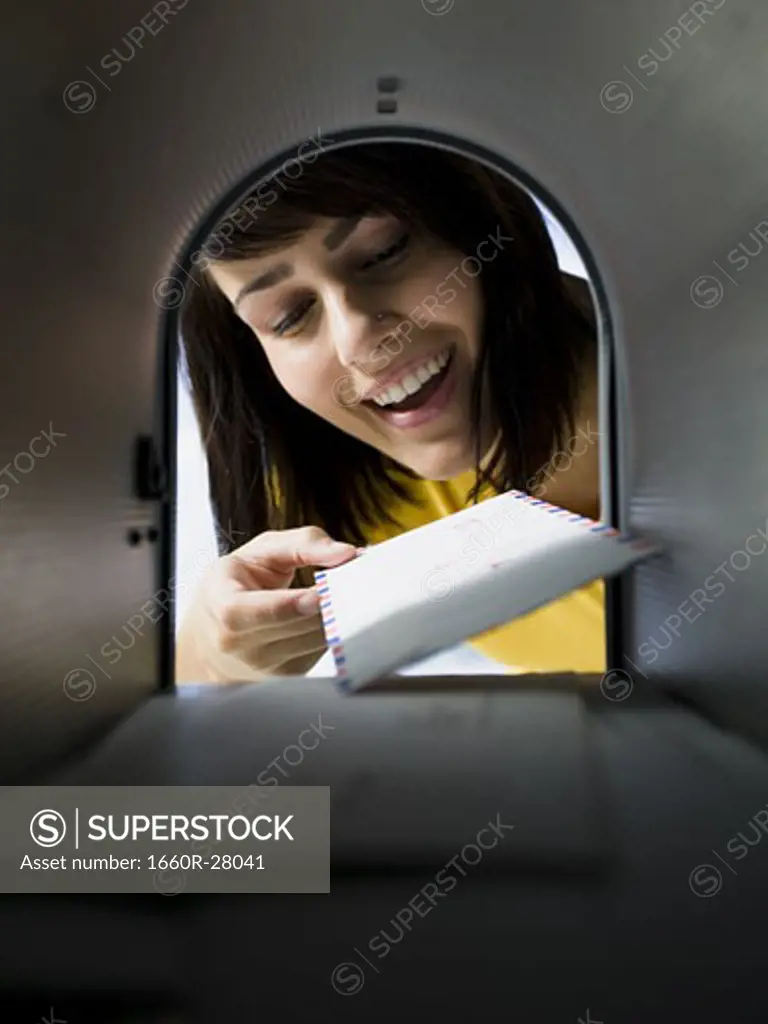 Close-up of a young woman looking at mail in a mailbox