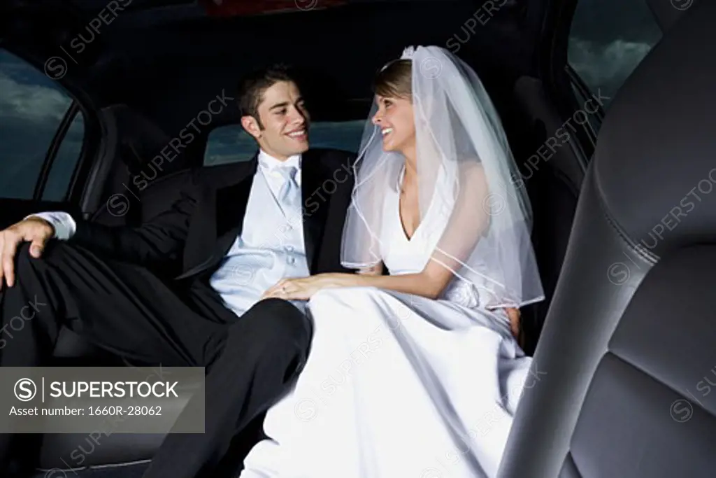 Close-up of a newlywed couple sitting in a car and looking at each other
