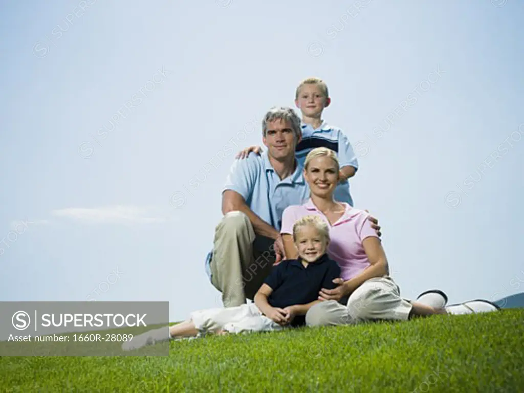 Low angle view of parents and their two children sitting on grass
