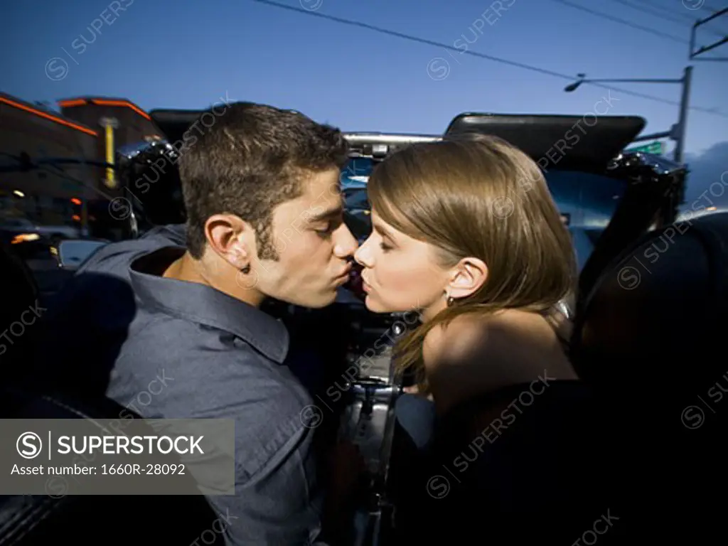 Profile of a young couple sitting in a car and kissing