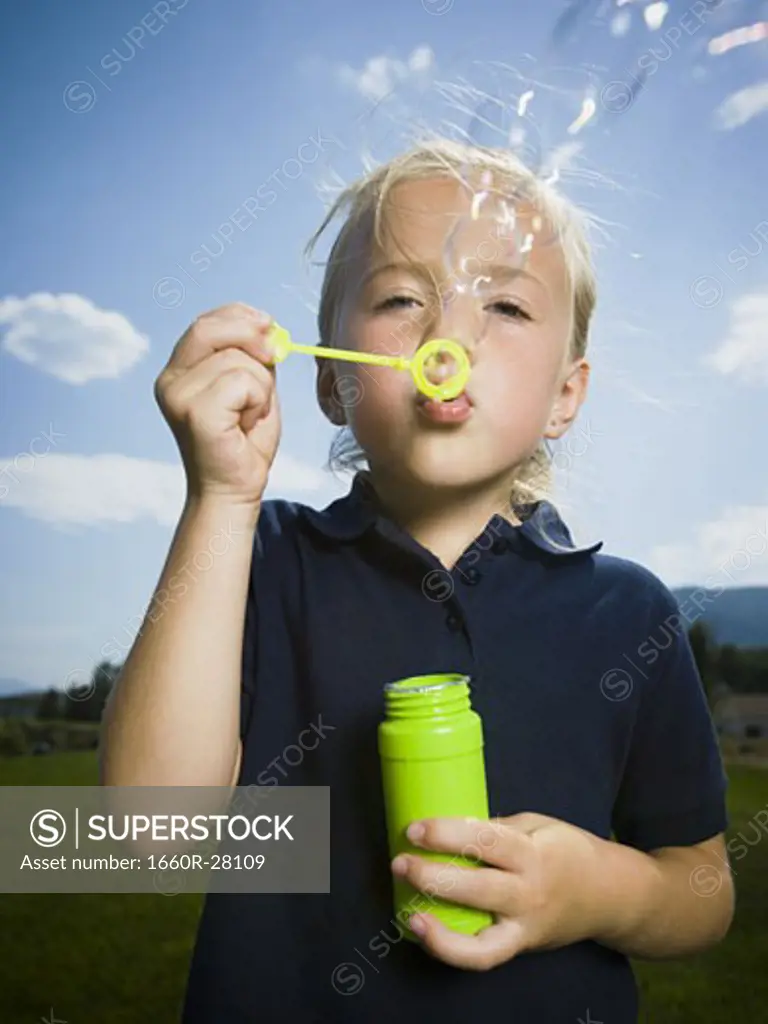 Close-up of a girl blowing bubbles with a bubble wand