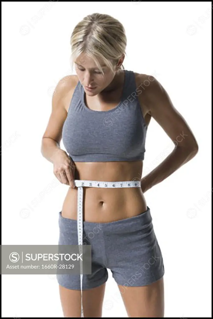 Close-up of a young woman measuring her waist with a measuring tape