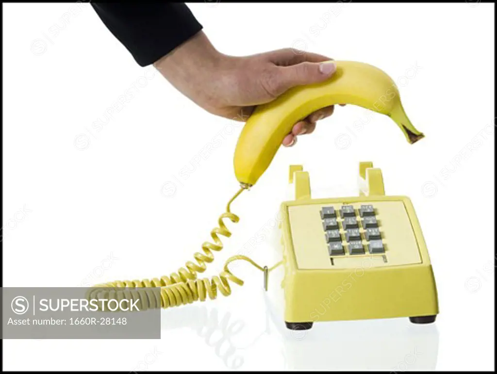 Close-up of a person's hand picking up a banana telephone receiver