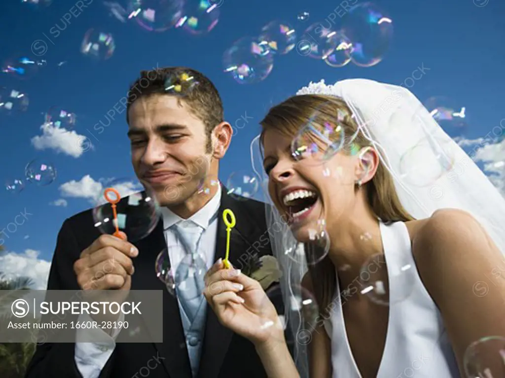Close-up of newlywed couple blowing bubbles with a bubble wand