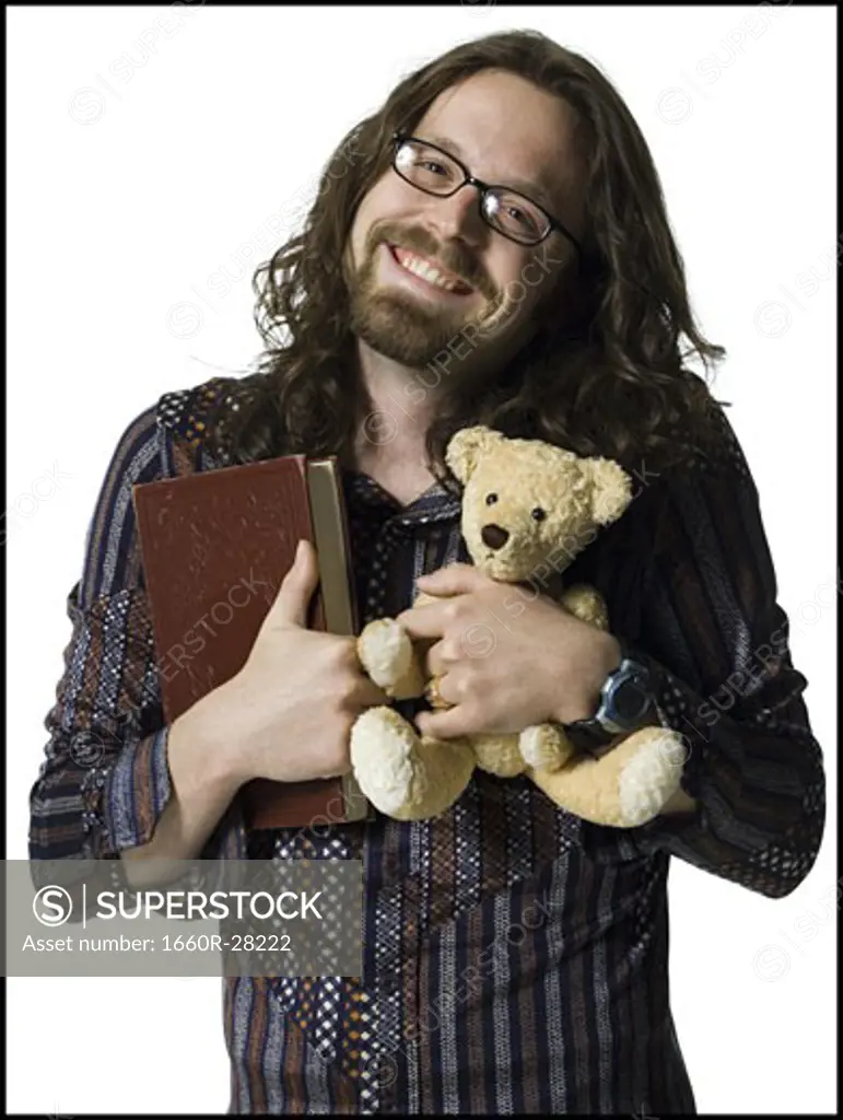 Portrait of a young man holding a book and a teddy bear