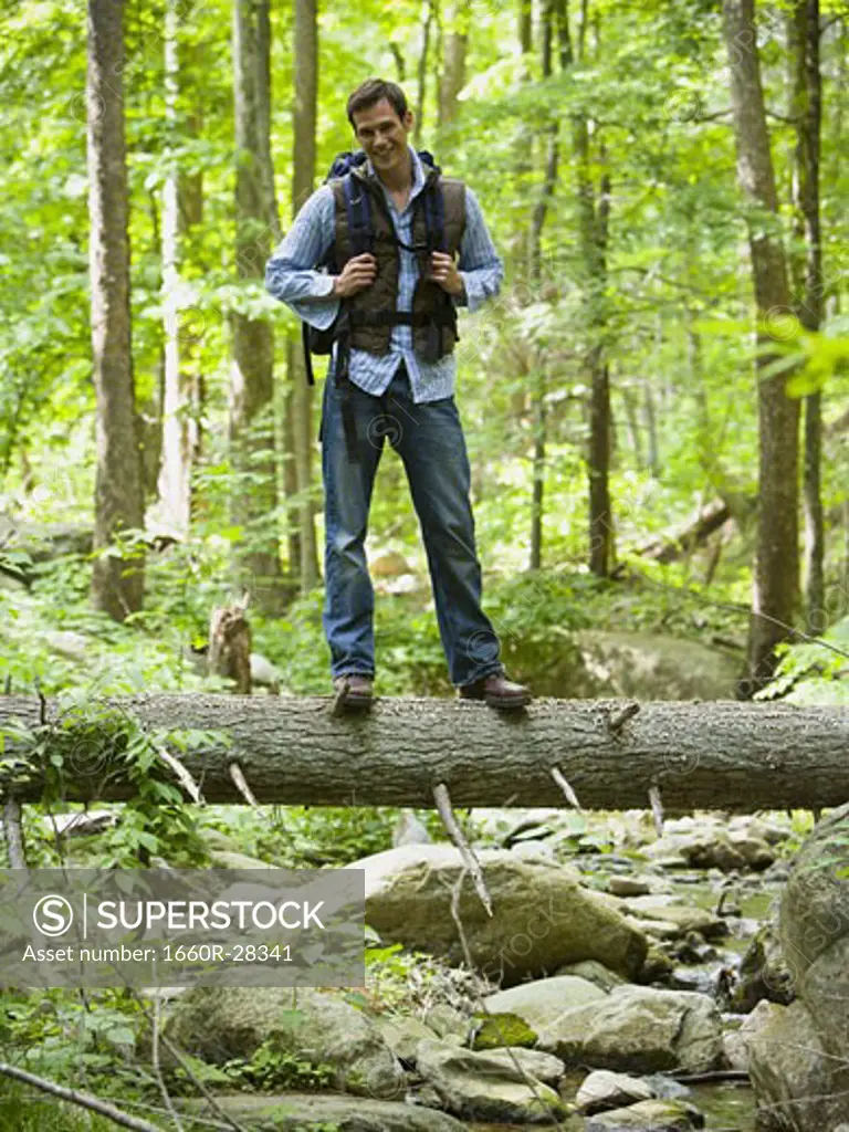Portrait of a young man standing on a fallen tree