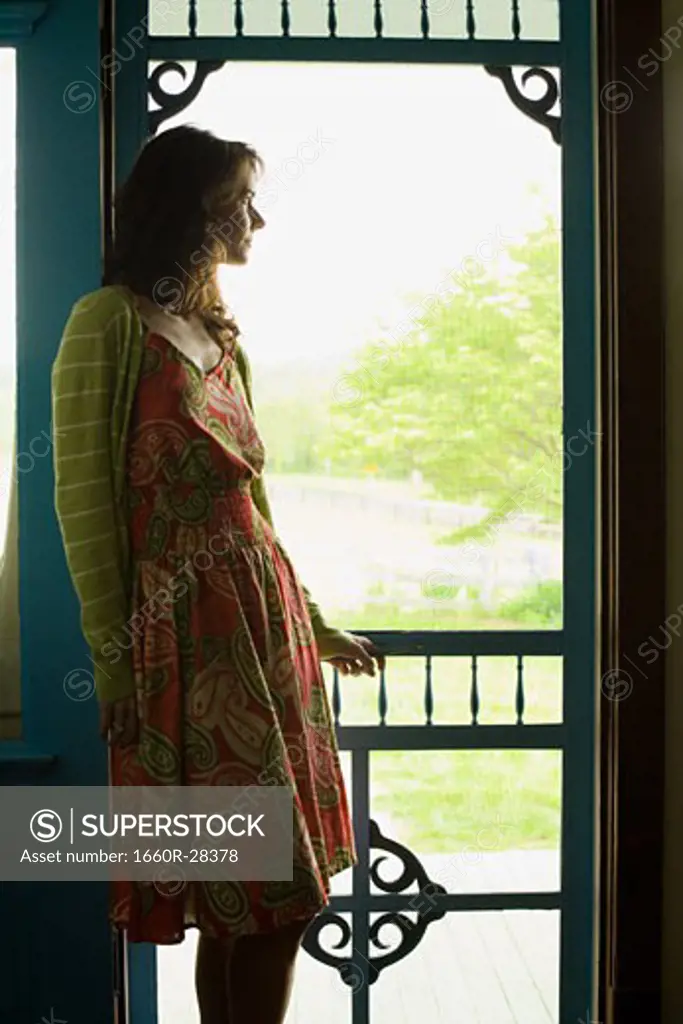 Profile of a woman leaning against a door and looking away