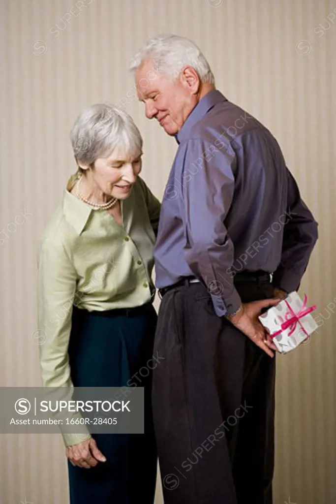 Rear view of a senior man holding a gift with a senior woman looking at him