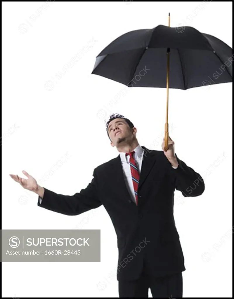 Businessman holding an umbrella and looking up