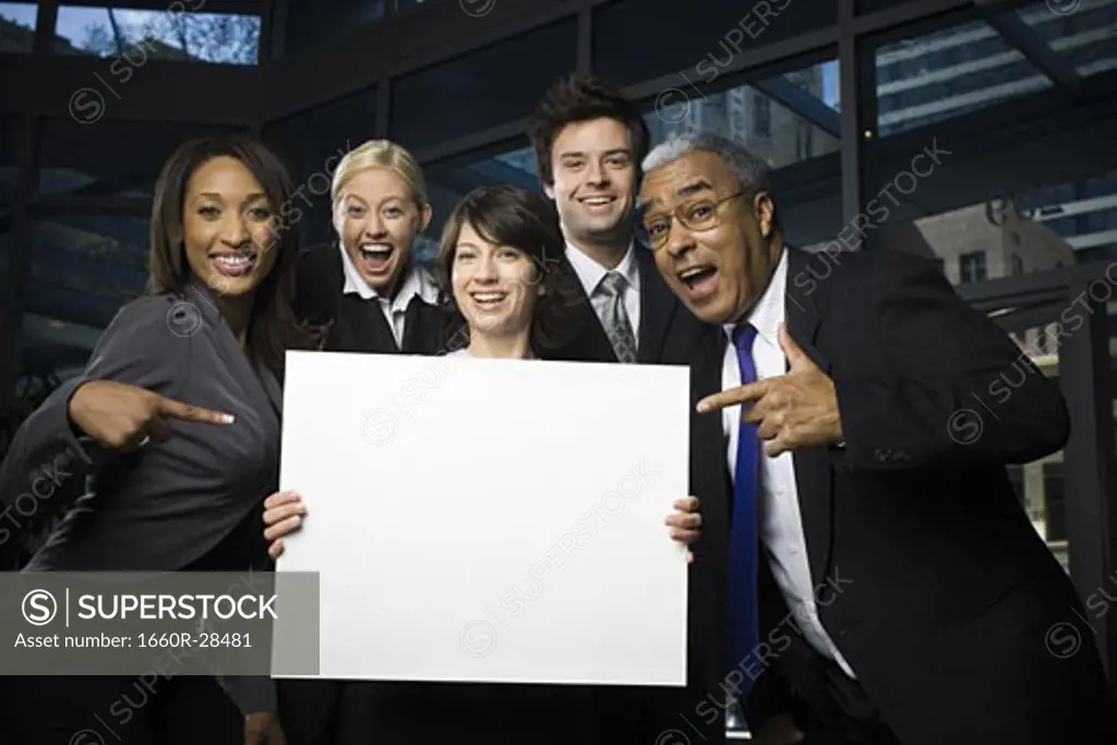Portrait of five business executives standing with a blank sign