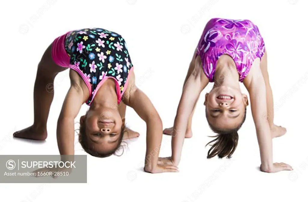 Young female gymnasts bending backwards