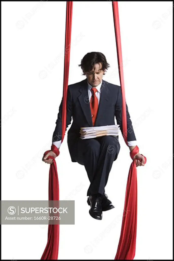 Businessman tangled in red drapes
