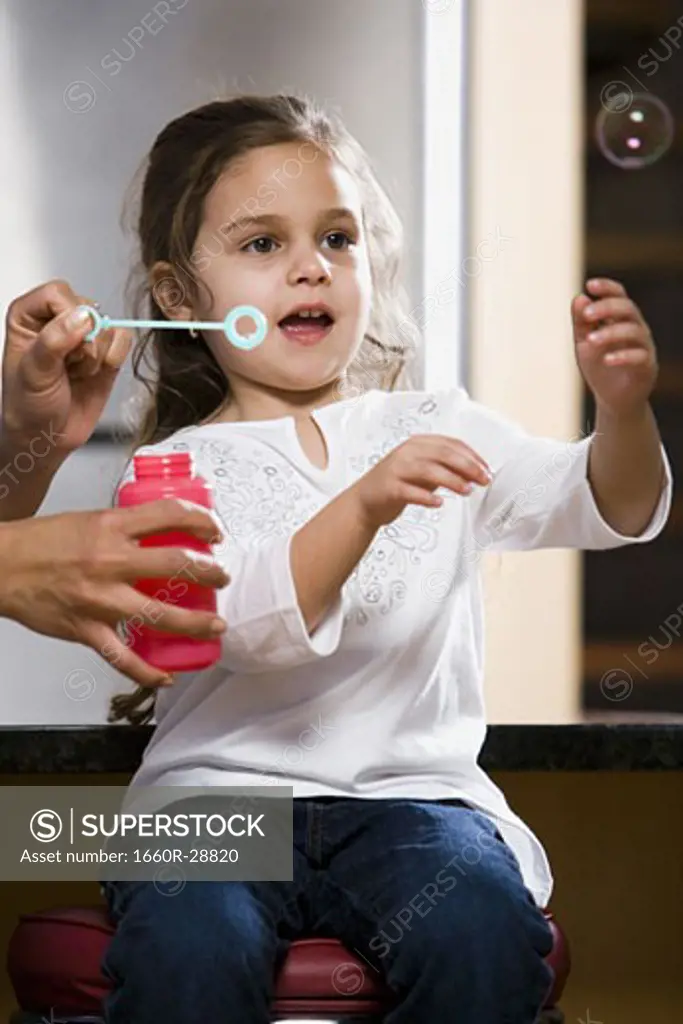 Mother and young daughter blowing bubbles