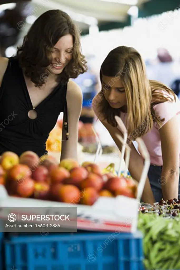 Two teenage girls at a fruit stand