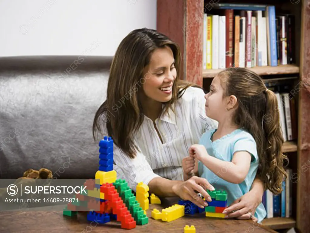 Mother and young daughter playing with building blocks