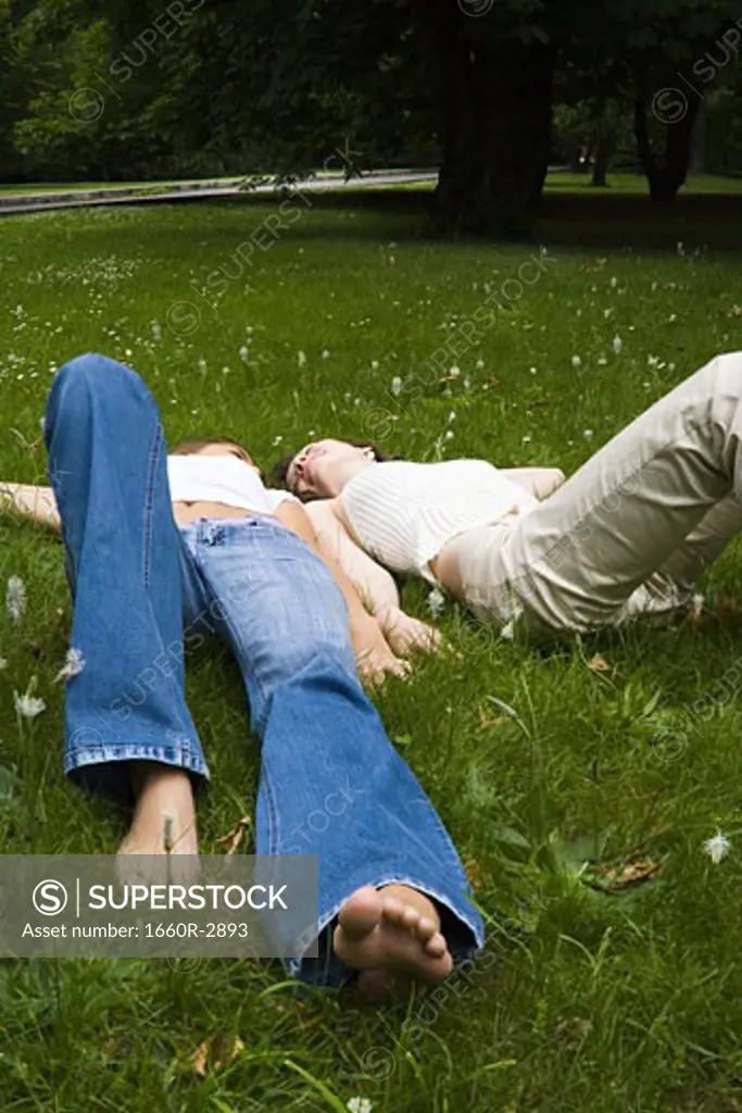 High angle view of two teenage girls lying on the grass