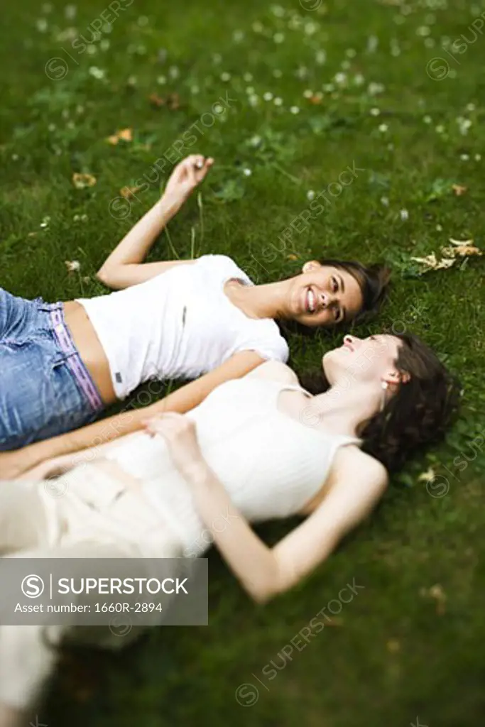 High angle view of two teenage girls lying on the grass