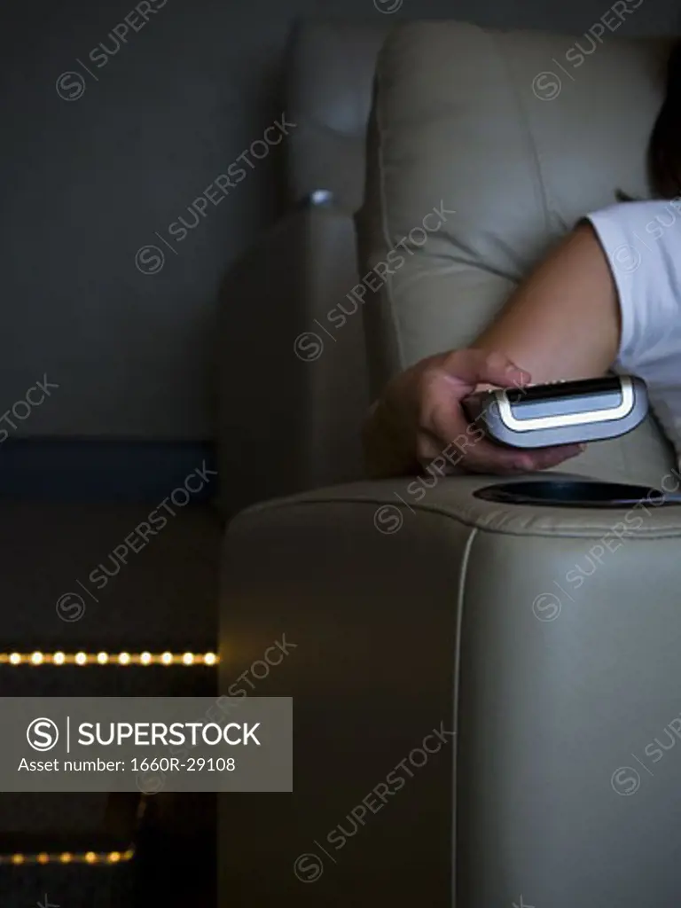 Hand holding remote control in home theater
