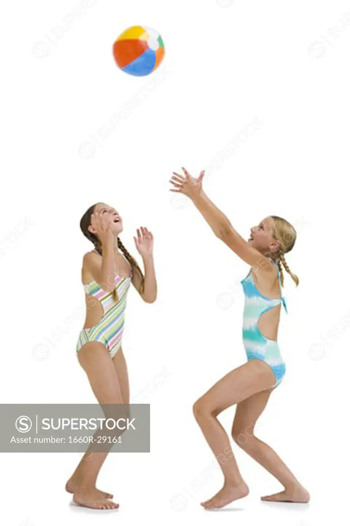 Young sisters on vacation playing with a beach ball