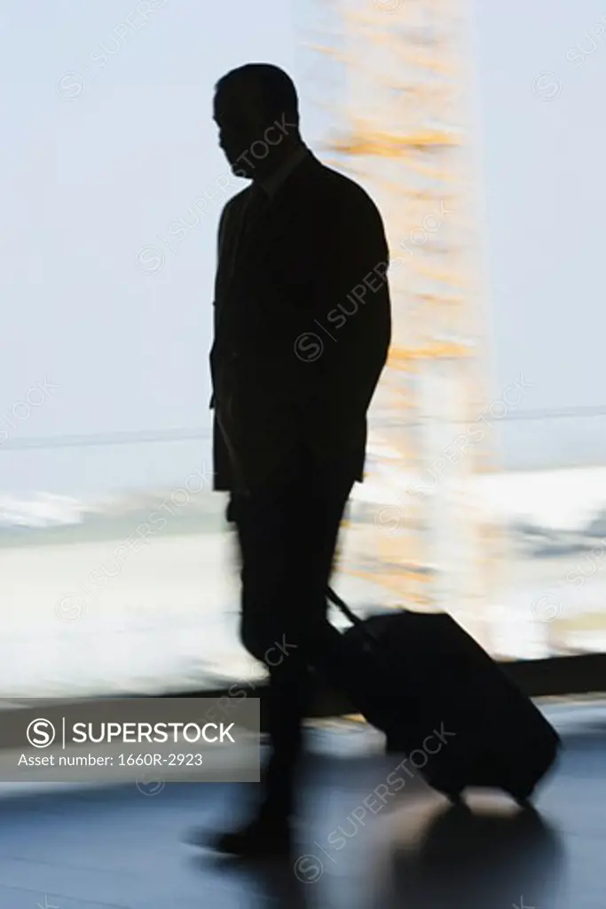 Silhouette of a businessman walking with a trolley