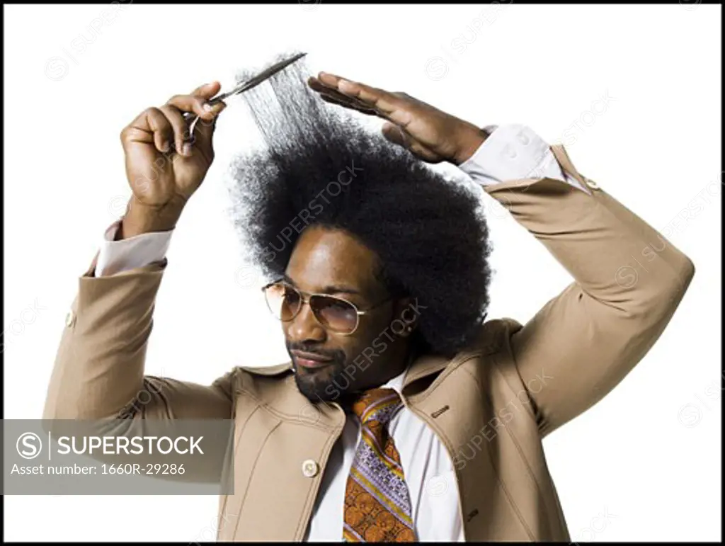 Man with an afro in beige suit combing with a hair pick