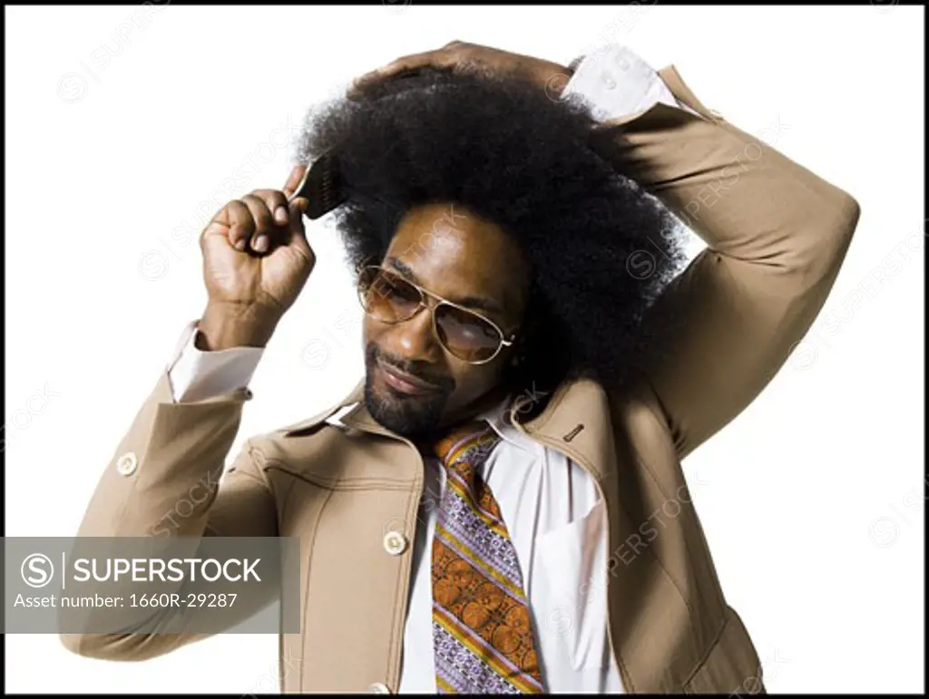 Man with an afro in beige suit combing with a hair pick