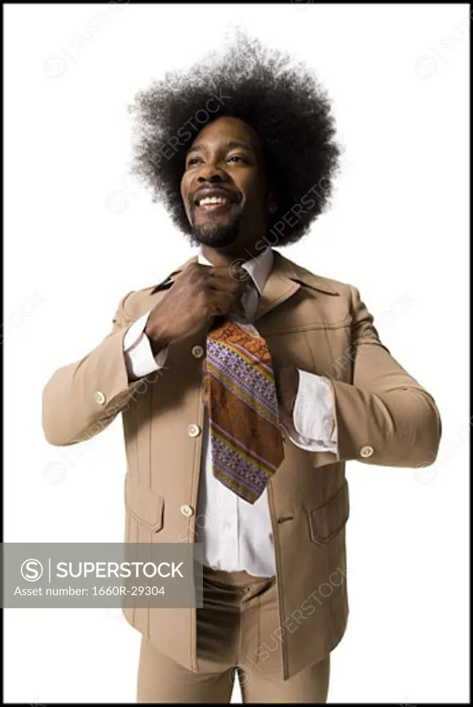 Man with an afro in beige suit adjusting necktie