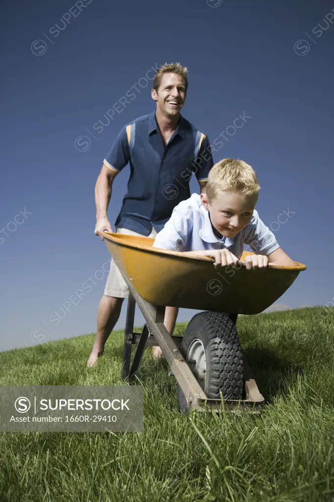 Father pushing son in a wheelbarrow