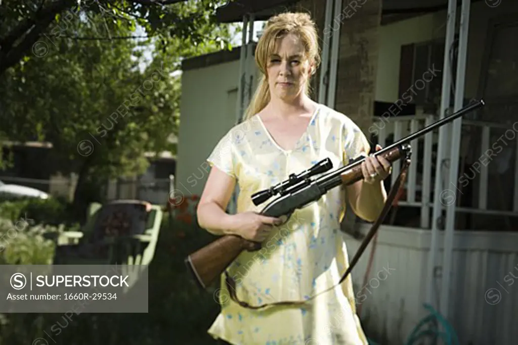 Woman in trailer park with a rifle