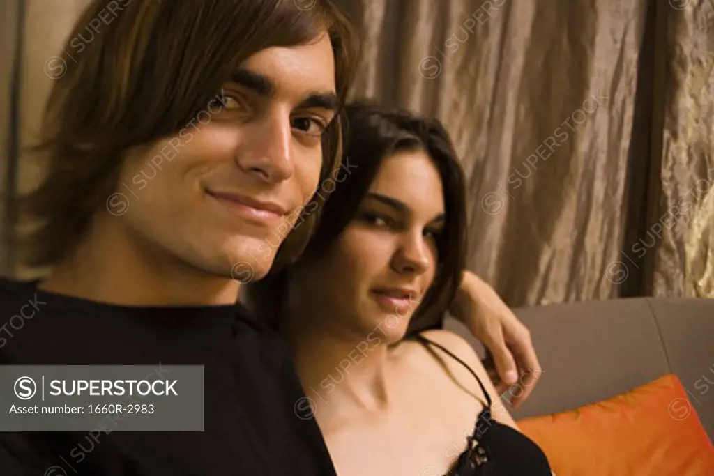 Close-up of a young man and a young woman sitting on a couch