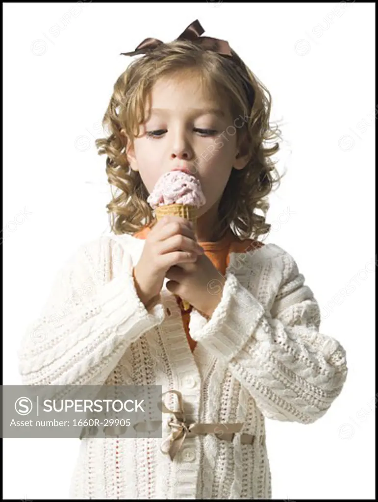 Smiling young girl in white sweater eating ice cream cone