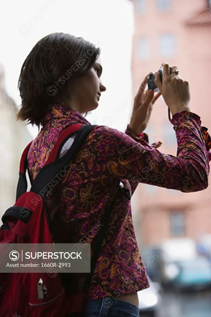 Low angle view of a young woman taking a photograph