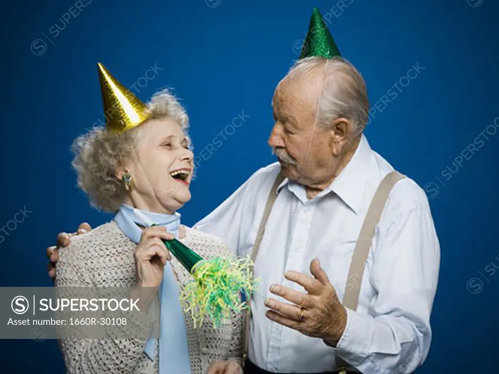 Older couple with noisemakers and party hats