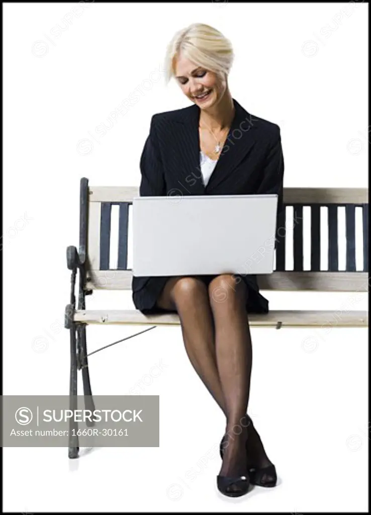 Businesswoman sitting on bench with laptop